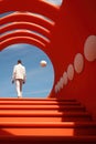 A man in a white suit is walking up some stairs in red tunnel. Minimalism