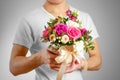 Man in white t shirt holding in hand rich gift bouquet. Composition of flowers in a pink hatbox. Tied with wide white ribbon and