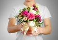 Man in white t shirt holding in hand rich gift bouquet. Composition of flowers in a pink hatbox. Tied with wide white ribbon and Royalty Free Stock Photo