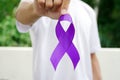 A man with white t-shirt holding a luxury purple ribbon. Purple ribbon with pancreatic cancer awareness.