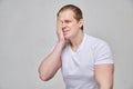 A man in a white T-shirt massages his eye - terrible pain due to inflammation