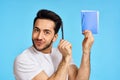 man in white t-shirt notebook with pen student blue background