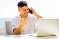 man in white t-shirt talking by phone while remote working at sunny beach in cafe Royalty Free Stock Photo