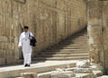 Man in a white traditional outfit walking through Jerusalem.