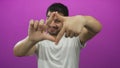 Man in white tshirt frames view with hands and smiles in purple studio; creativity joy imagination Royalty Free Stock Photo