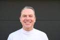 A man in a white turtle neck t shirt giving a very big smile to the camera