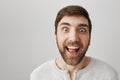 Man who lost weight looks with crazy eyes at sweets. Studio shot of funny weird guy with beard and strange smile Royalty Free Stock Photo