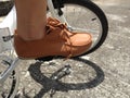 Man who wears brown shoe is riding white bicycle