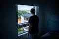 Man and window in dark room. Spying neighbor or snooping. Loneliness, shame or melancholy. Depressed, sad, moody. Royalty Free Stock Photo