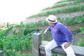 Man in straw hat sitting in vineyard on bench on hill