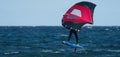 A man is wing foiling using handheld inflatable wings and hydrofoil surfboards in a blue ocean Royalty Free Stock Photo