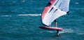 A man is wing foiling using handheld inflatable wings and hydrofoil surfboards in a blue ocean