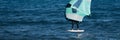 A man is wing foiling using handheld inflatable wings and hydrofoil surfboards in a blue ocean