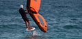 A man is wing foiling using handheld inflatable wings and hydrofoil surfboards