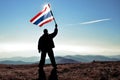 Man winner waving Thailand flag on top of the mountain peak