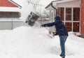man in winter clothes shoveling snow during snowstorm