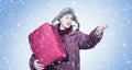 A man in winter clothes, who was late for transport, holds a red suitcase in his hands, making a hand gesture on a blue background