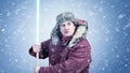 Man in winter clothes with a wooden lightsaber in his hands on a blue background with falling snow