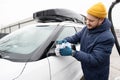Man wipes american SUV car mirror with a microfiber cloth after washing in cold weather Royalty Free Stock Photo