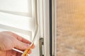 man wipes window frame with a degreaser and glues a sealing rubber tape on it for noise insulation