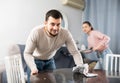 Man wiping furniture with rag while woman hoovering couch Royalty Free Stock Photo