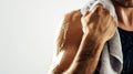 Man wiping sweat off his neck with a towel, highlighting his muscular physique