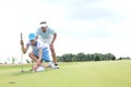 Man with woman aiming ball on golf course against sky Royalty Free Stock Photo