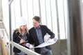 Man and woman architects or engineers work together discussing with blueprint in the inside the construction building site