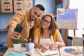 Man and woman artists drawing on notebook make selfie by smartphone at art studio