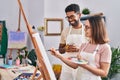 Man and woman artists drinking coffee drawing at art studio