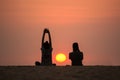 Man and woman on the background of beautiful sunset. Yoga and the photographer sit on the beach to watch the sunset
