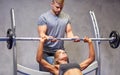 Man and woman with barbell flexing muscles in gym