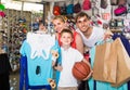 man and woman with boy choosing t-shirts and other goods in sport shop