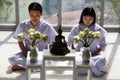 Man and woman Buddhist in white dress sitting and doing meditation in front of set of altar table with buddha image. Idea for Royalty Free Stock Photo