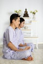 Man and woman Buddhist in white dress sitting and doing meditation in front of set of altar table with buddha image. Idea for Royalty Free Stock Photo