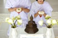 Man and woman Buddhist in white dress sitting  in front of set of altar table and paying homage to buddha image. Idea for ritual Royalty Free Stock Photo