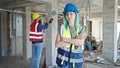 Man and woman builders standing with arms crossed gesture working at construction site