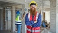 Man and woman builders standing with arms crossed gesture working at construction site