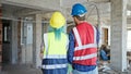 Man and woman builders standing backwards at construction site