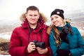 A man and a woman with cameras travel in winter