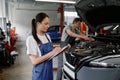 Man and woman car mechanic talking discussing causes of car failure Royalty Free Stock Photo