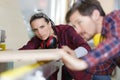 man and woman carpenter measuring wooden plank with tape measure