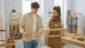 A man and a woman in a carpentry workshop collaboratively inspecting wooden frames Royalty Free Stock Photo