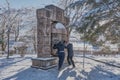 A man and a woman in casual warm clothes turn the egg of desires. The resort park in the winter. Stone sculpture sundial Royalty Free Stock Photo