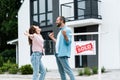 Man and woman celebrating near house and board with sold letters