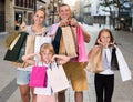 Man and woman with children holding shopping bags in city