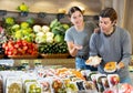 Man and woman choosing packaged carrots and sliced papaya to buy in fruit and vegetables shop Royalty Free Stock Photo