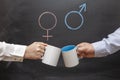 A man and a woman clink mugs against a background of gender symbols. Concept of gender equality Royalty Free Stock Photo