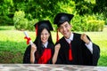 Man and woman couple dressed in black graduation gown or graduates with congratulations with hold diploma in hand is sitting Royalty Free Stock Photo