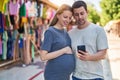 Man and woman couple expecting baby using smartphone at street market Royalty Free Stock Photo